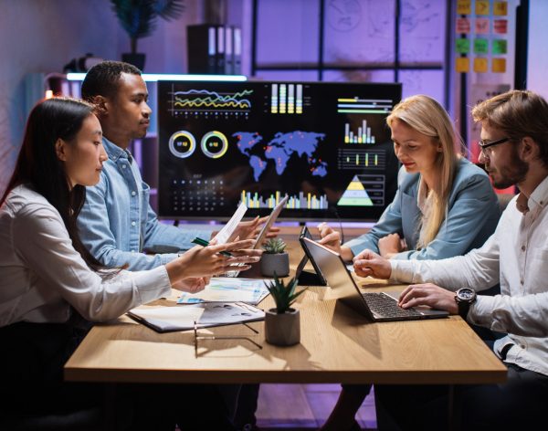 International team of competent financiers using modern tablets and laptops while having meeting at modern office. People working with financial charts and graphs. Business and technology concept.