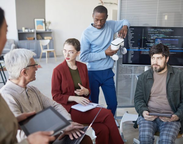High angle view at contemporary diverse business team sitting in circle during strategy meeting, focus on young businesswoman in center